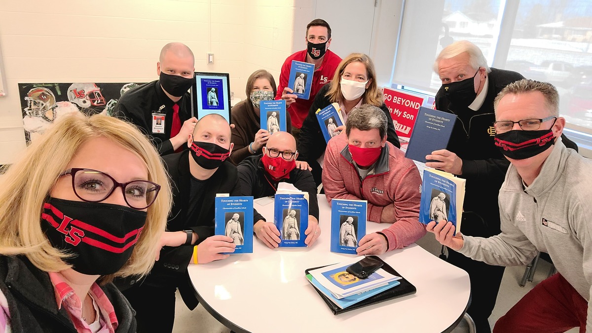 team photo holding up books